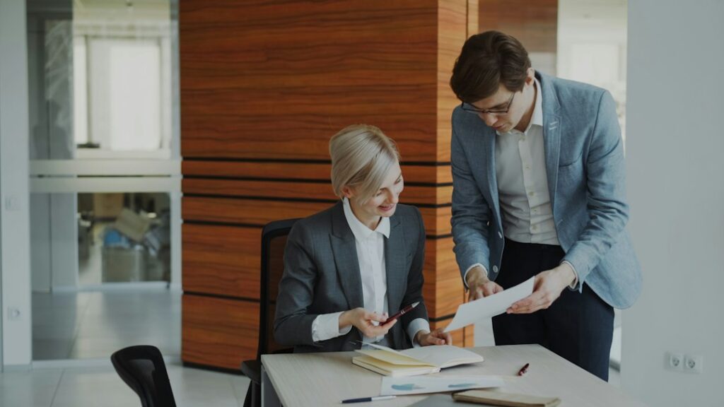 Tenant and landlord review a commercial lease at a table with floor plans, keys, and financial documents.
